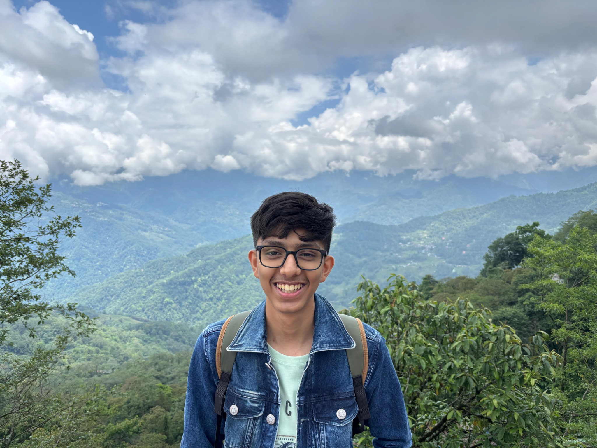 Portrait of Om Joshi standing outdoors in front of mountains.